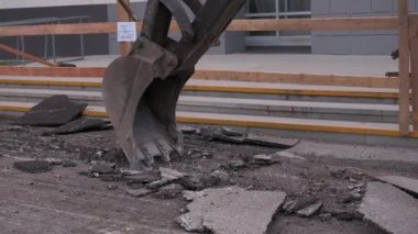 Kazı makinesinin asfaltı kırdığı yakın plan. Şarjör. Kazı makinesi eski asfalt tabakasını yaz günü kaldırır. Kazıcı yollarda yol yüzeyini değiştirir. 