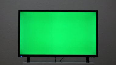LCD akıllı televizyon, oturma odasının arka planında yeşil ekran var. Kavram. Modern bir televizyonun krom anahtar ekranı