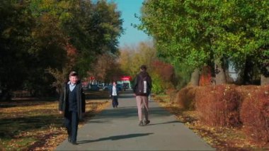 Sırbistan, Belgrad - 5 Eylül 2022: Şehir merkezinde insanlar park yolunda yürüyor. Şarjör. Çocuk güneşli bir sonbahar gününde parktaki patikada okula gidiyor. İnsanlar iş için park yoluna giderler.. 