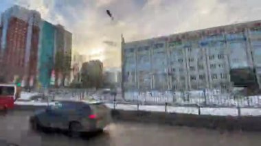 Hareket halindeki bir araçtan görüntü. Şarjör. Baharda, eriyen karlar ve hareket halindeki arabalarla birlikte binaların olduğu yol manzarası. Yüksek kaliteli FullHD görüntüler