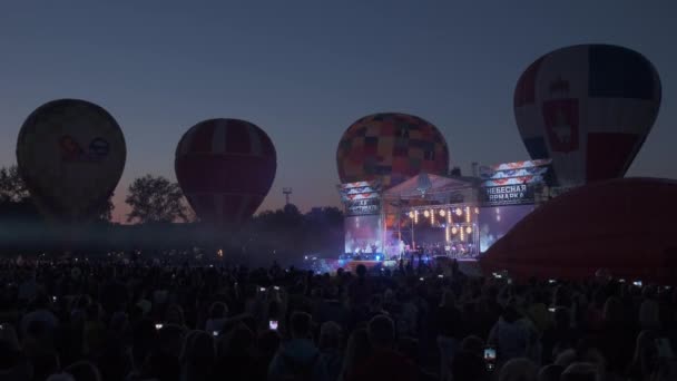 風船によるミュージカルコンサート クリップ 夜のフィールドで風船で音楽コンサートをする人々の群れ フライトのための群衆と風船との夜のコンサート — ストック動画