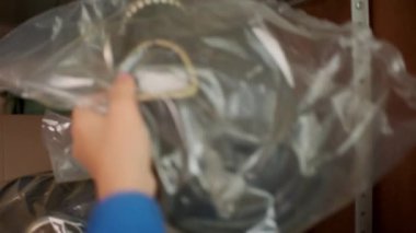 Depoya mal koyan bir kadının yakın çekimi. Şarjör. Paketteki eşyalar depodaki raflara konur. Paketlenmiş öge odadaki raflarda saklanır. 