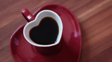 Kadın kalp bardağında kahve yapmış. Kavram. Koyu kahve ve kırmızı kalp şeklinde güzel bir kupa. Romantik bir kalp şeklinde kupa ve romantik bir günde kahve.. 