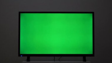 Yeşil arkaplanı olan TV ekranının yakın çekimi. Kavram. Yeşil ekranlı plazma televizyon. Modern TV, yeşil ekran komodinli komodinin üzerinde.. 