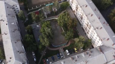 Kare şeklindeki konut evleriyle çevrili küçük yeşil bir avlu. Stok görüntüleri. Küçük bir spor stadyumu olan yerleşim alanının üst hava manzarası.