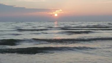 Nehir kıyısındaki güzel dalgaları kapatın. Yaratıcı. Dalgalanan su yüzeyinin üzerinde açık pembe gün doğumu