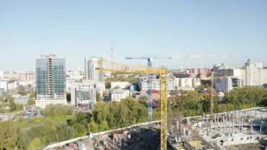 Yüksek vinçler ve profesyonel işçilerle spor stadyumu kuruyor. Stok görüntüleri. Güneşli bir günde şehirde inşaat alanı 