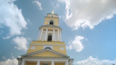 Yüksek sarı ve beyaz kulesi olan Ortodoks kilisesinin resimli görüntüsü. Şarjör. Yazın mavi gökyüzünün arka planında güzel Hıristiyan kilisesi