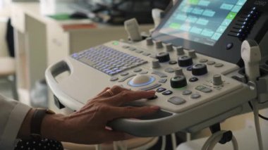 Sırbistan, Belgrad - 13 Eylül 2023: Kadın doktor eli ultrason tarayıcısı kullanarak tıbbi muayene yapıyor. Şarjör. Ultrason makinesi ve doktor eli üzerinde çalışıyor.