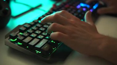 Genç oyuncu video oyunu oynuyor ya da renkli klavyeyle yazı yazıyor, kapat. Şarjör. Oyuncu, oyun aydınlatma klavyesi, siber spor kavramını kullanır 