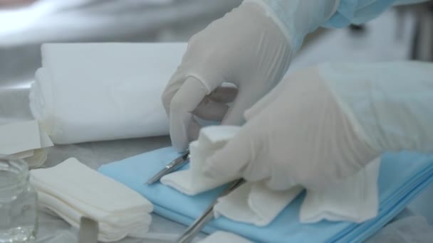 手術の準備 手術ツール付きのテーブル アクション 無菌ガーゼを切断するゴム手袋のスクラブ看護師の手 — ストック動画