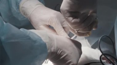 Cerrahların elleri ameliyat sırasında yakınlaşır. Başla. Cerrahların elleri ve asistanları hastayı ameliyat eder. Hasarlı veya enfekte olmuş organ ameliyatı.