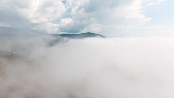 地平線上に山頂に位置する厚い雲の最上層ビュー ショット 山の上から濃い雲で曇った空を飛ぶ 白い雲の間の地平線上の緑の山の上の風景 — ストック動画