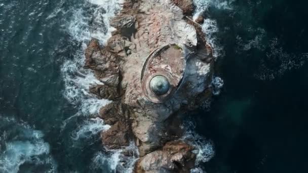 在海石上俯瞰灯塔 被遗弃的灯塔在海上岩石海角的边缘 阳光明媚的日子里 蓝色的波浪拍打着石板 灯塔映衬着 — 图库视频影像
