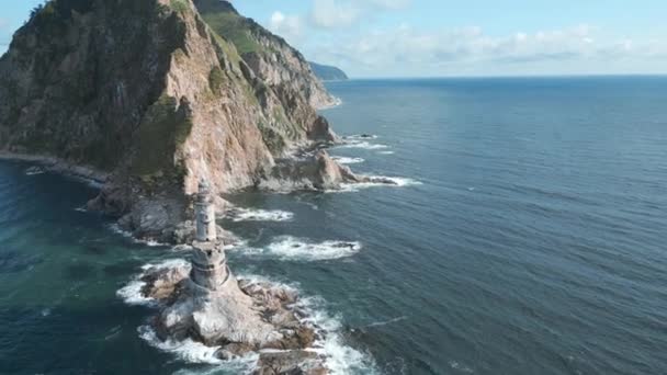 放棄された灯台のある海の岩のトップビュー クリップ 海の古い灯台と岩の岬の美しい景色 晴れた夏の日に海で岩の岬の風景灯台 — ストック動画