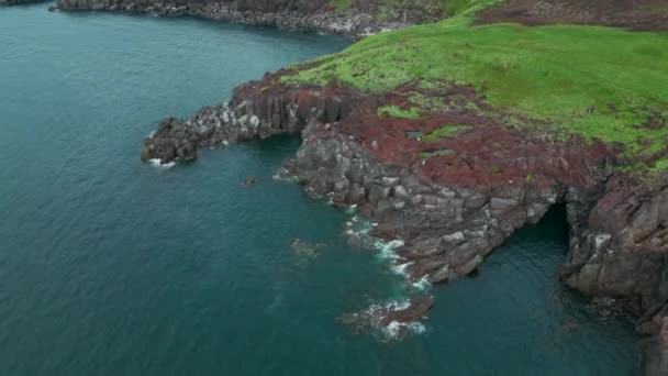 小さなリプルを持つ美しい石の崖と緑の海水 クリップ ロッキーコーストの空中眺望 — ストック動画