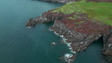 Resimli uçurumun ve gök mavisi denizin havadan görünüşü. Şarjör. Yeşil çimenler ve taşlı kıyılar