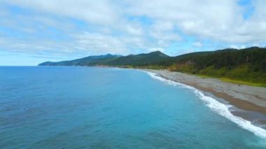Ufukta dağlar olan kıyı şeridinin en üst manzarası. Şarjör. Yeşil ormanı ve okyanus kıyısında dağları olan bir ada. Cennet, dağlarla dolu adanın vahşi sahillerinde dinlenmek için.. 