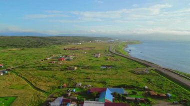 Deniz kıyısına giden yolu olan köyün üst manzarası. Şarjör. Güneşli bir yaz gününde yol ve köyle kıyı şeridi. Güzel kıyı manzaralı köy ve deniz güneşli ufuk.. 