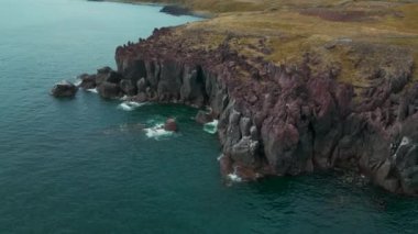 İzlanda 'daki kayalıklar ve manzara, hava manzarası. Şarjör. Gök mavisi deniz ve kıyının dik kayalık yamacı