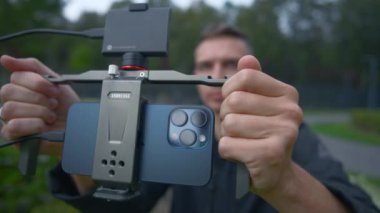 İngiltere, Londra - 15 Eylül 2023: Adam telefonda dengeleyiciyle ateş ediyor. Başla. Yeni iPhone 15 'te sinematik çekim. Yeni iPhone 15 ile sinematik efekt için dengeleyiciyle çekim yapılıyor