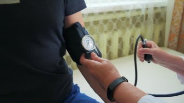 Doktor erkek bir hastanın vücut basıncını ölçmek için mekanik tonometre kullanır. Şarjör. Sağlık ve ilaç kavramı