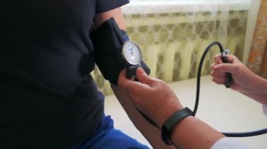 Doktor erkek bir hastanın vücut basıncını ölçmek için mekanik tonometre kullanır. Şarjör. Sağlık ve ilaç kavramı