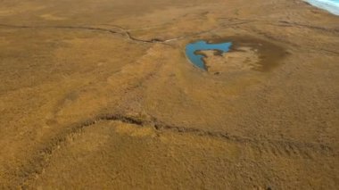 Kurumuş sarı tarlada küçük gölü olan huzurlu kırsal alan. Şarjör. Sonbahar vadisi ve deniz kıyısı