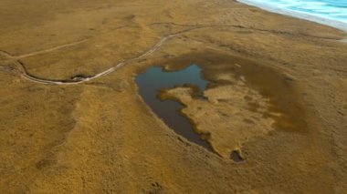 Kurumuş sarı tarlada küçük gölü olan huzurlu kırsal alan. Şarjör. Sonbahar vadisi ve deniz kıyısı