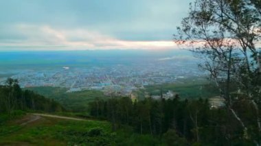 Yeşil dağlardan turist kasabasına doğru uçan hava aracı. Şarjör. Tepenin yamacındaki yeşil ağaçlar ve bulutlu gökyüzü