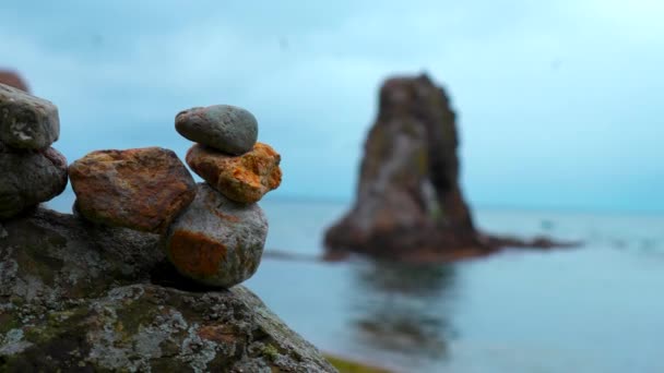 在海滩上堆放岩石的特写镜头 石头堆放在海洋岩石模糊的背景上 堆放在炮塔中的石子 耸立在阴沉沉的大海中 — 图库视频影像