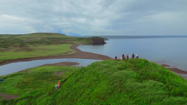 観光のコンセプト 丘の上の人々のグループ クリップ 緑の草と海岸の空中ビュー — ストック動画
