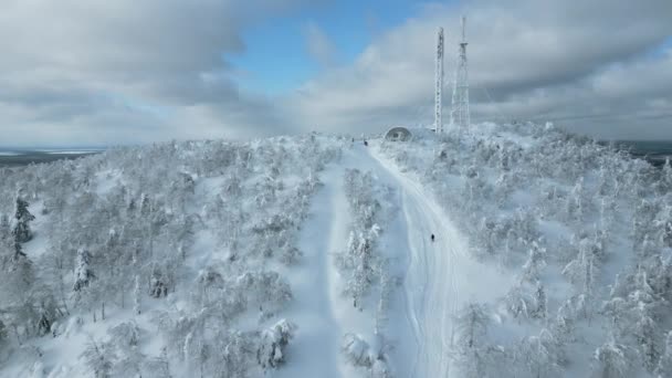 シベリアの厳しい冬の森を巡るフライト クリップ 白い山とその上に凍った天気予報塔 — ストック動画