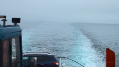 Bulutlu bir havada, arabası olan bir gemi denize açılır. Şarjör. Denizdeki arabayla feribota binmek. Bulutlu bir günde yelkenli gemisinin bıraktığı çizginin görüntüsü. 