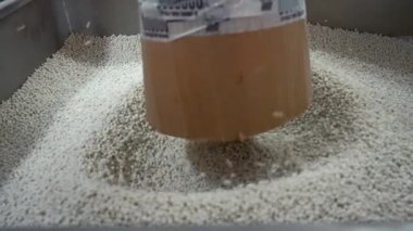 Üretimdeki polimer granüllere yakın çekim. Yaratıcı. Ekstrüzyon işlemi ve plastik granüllerin kurutulması. Endüstriyel atölyede beyaz plastik topaklar yığını. 