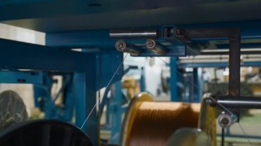 Fabrikada kablolarla dönen bobinler. Yaratıcı. Metalurji şirketinde kabloların bobinlere dağıtılması ve kıvrılması. Çıkarma işlemi sırasında polimer çizgilerin bobinlere sarılması. 
