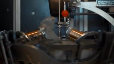 Dönen bobinleri ve kabloları olan otomatik bir makine. Yaratıcı. Bobinler kıvrımlı tellerle kümelenir. Endüstriyel makine dönüyor ve bakır kabloyu kuruyor. 