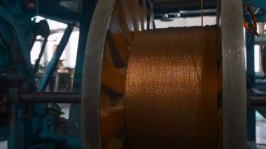 Fabrikada metal kablolarla dönen bobinler. Yaratıcı. Metalurji fabrikasındaki bobinlere metal lifler sarılmış. Endüstriyel ölçekte bakır tel bobinlerine çevirme işlemi. 