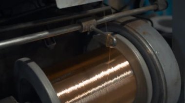 Sarmalı sarmalayan bakır kabloya yakın çekim. Yaratıcı. Parlak bakır tel, metalurji fabrikasındaki bobine sarılmış. Bakır kablo üretimi. 