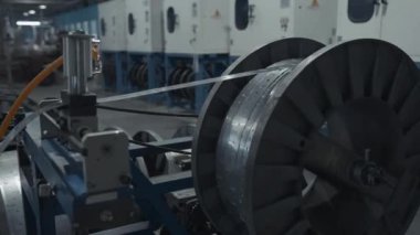 Bobbin üzerinde metal, uzun, dar tabakalar. Yaratıcı. Fabrika atölyesinde büyük bir makara, endüstriyel arka plan