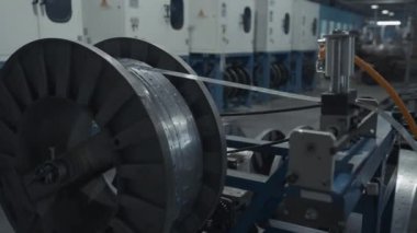 Bobbin üzerinde metal, uzun, dar tabakalar. Yaratıcı. Fabrika atölyesinde büyük bir makara, endüstriyel arka plan