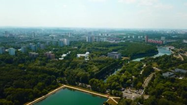 Güneşli yaz gününde baraj ve nehir manzaralı bir şehir. Yaratıcı. Yaz günü barajı ve kanalı olan güzel yeşil bir şehir. Yeşil parkları ve temiz kanalı olan modern şehrin silüeti.