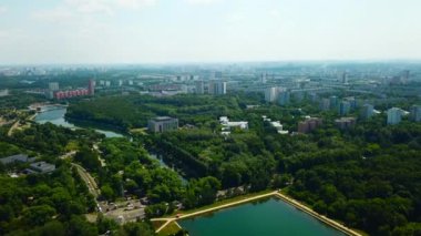 Güneşli yaz gününde baraj ve nehir manzaralı bir şehir. Yaratıcı. Yaz günü barajı ve kanalı olan güzel yeşil bir şehir. Yeşil parkları ve temiz kanalı olan modern şehrin silüeti.