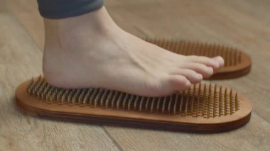 Tırnaklarıyla tahtada duran kadın ayakları, yaklaşın. Medya. Çıplak ayaklı kadın yoga tahtasında duruyor.