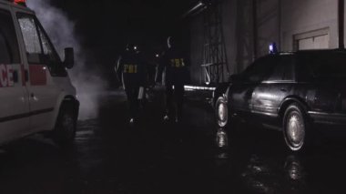 FBI ajanları olay yerinde, dikiz aynasından. Sahne. Federal Soruşturma Bürosu ajanları ağır çekimde yürüyorlar..