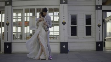 Güzel yeni evliler mutlu bir şekilde kucaklaşır. Başla. Takım elbiseli şık çift nazikçe sarılıyor. Yeni evli çiftimiz güneşli bir günde kucaklaşır..