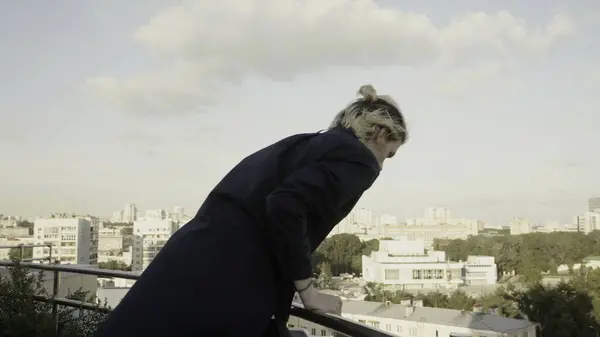 A man in a panic quickly climbs onto the roof canopy. Stock. A young man with white hair walking on the roofs of high-rise buildings. High quality 4k footage