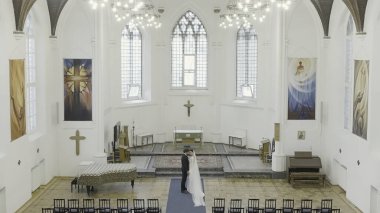 Tapınakta düğün fotoğrafçılığı. Aksiyon. Büyük gözlü, güzel bir geline sahip genç bir çift ve kilisede rahip bekleyen uzun boylu bir adam. Yüksek kalite 4k görüntü