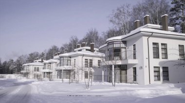 Kışın açık mavi gökyüzüne karşı sokakta duran lüks beyaz kulübelerin manzarası. Güzel kış kırsalları