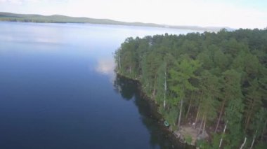 Ormanın ortasındaki küçük bir gölün havadan görünüşü. Güzel manzara denizi, orman ve kayalar 4K
